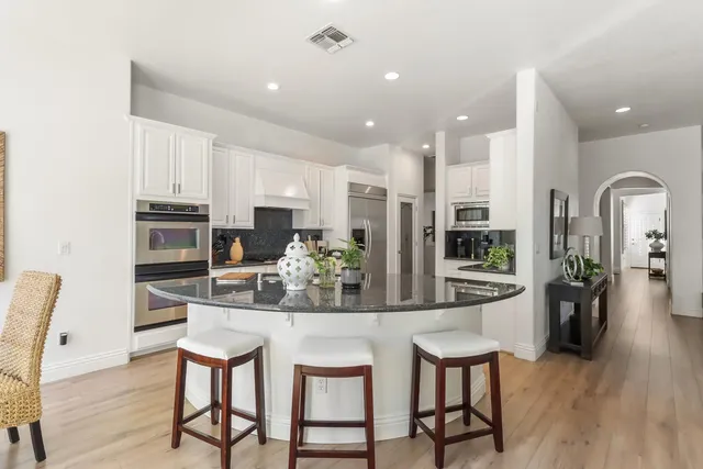 a dining room with stainless steel appliances kitchen island granite countertop a dining table chairs and granite counter tops