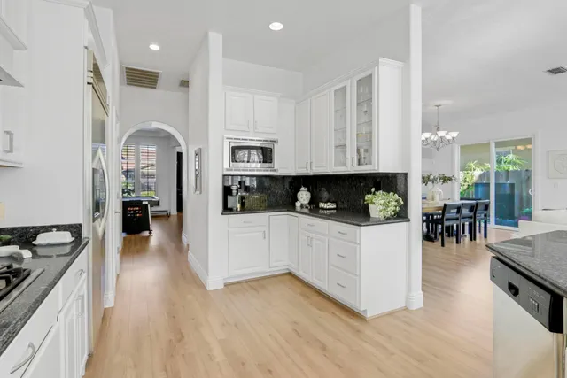 a kitchen with stainless steel appliances granite countertop a stove top oven a sink a dining table and chairs with wooden floor