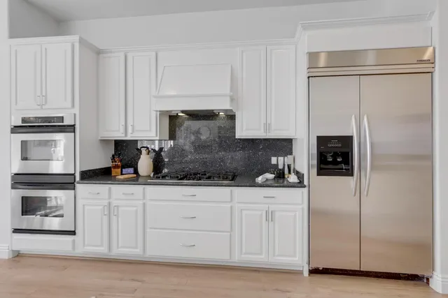 a kitchen with white cabinets and refrigerator