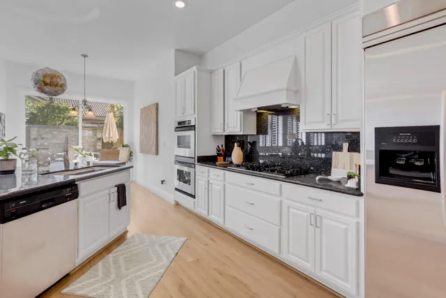 a kitchen with stainless steel appliances granite countertop a sink a stove and cabinets