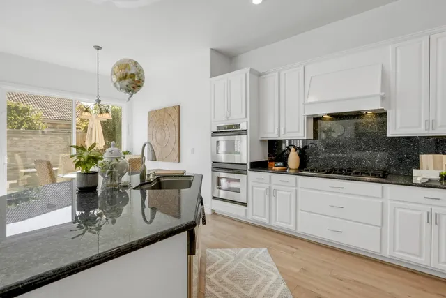 a kitchen with stainless steel appliances kitchen island granite countertop a stove a sink and white cabinets