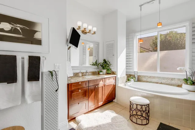 a spacious bathroom with a granite countertop sink mirror and bathtub