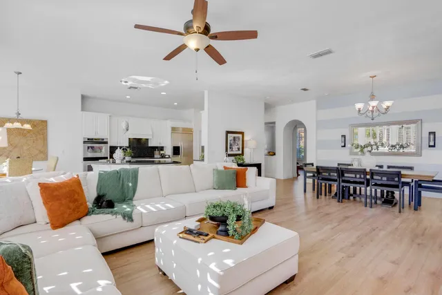 a living room with furniture kitchen view and a chandelier