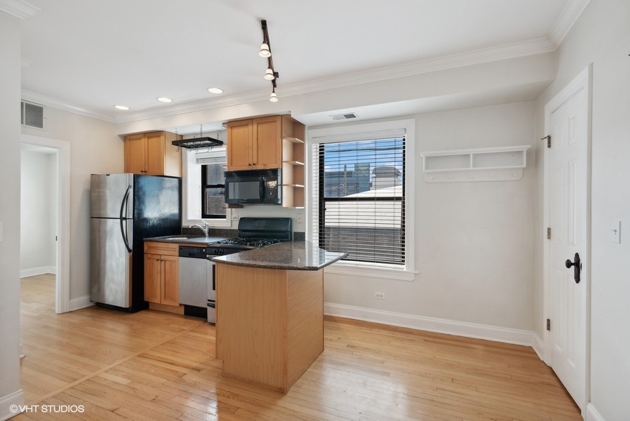 1137 West Grace Street, Unit 2E Chicago, IL 60613 - Photo 4 of 11 a kitchen with stainless steel appliances granite countertop a refrigerator a sink a stove and a cabinets