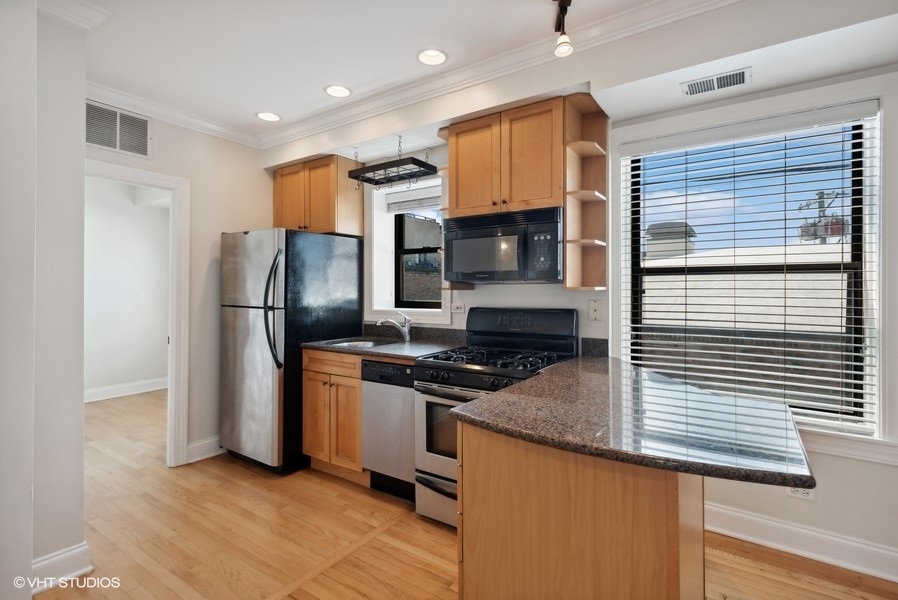 1137 West Grace Street, Unit 2E Chicago, IL 60613 - Photo 5 of 11 a kitchen with stainless steel appliances granite countertop a refrigerator a stove and a sink