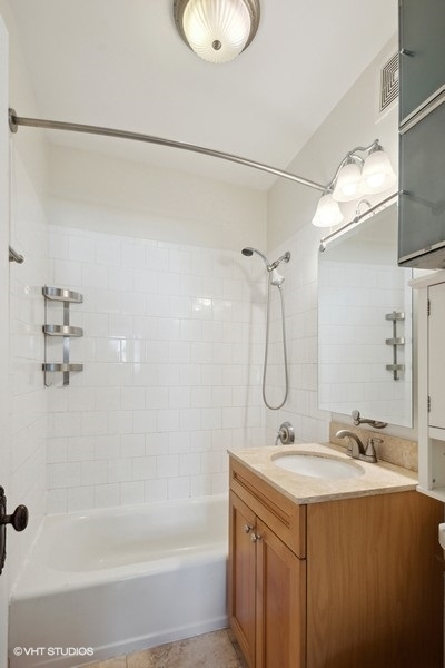 1137 West Grace Street, Unit 2E Chicago, IL 60613 - Photo 6 of 11 a bathroom with a granite countertop sink a shower and a mirror