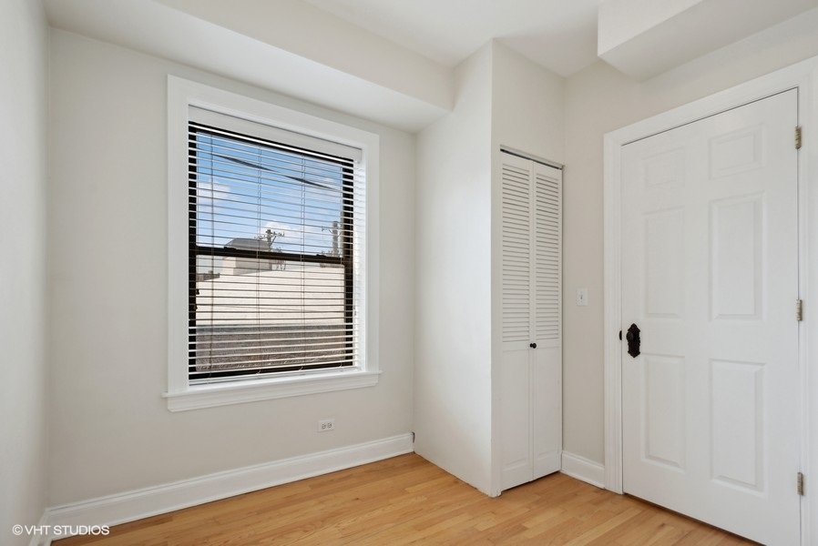 1137 West Grace Street, Unit 2E Chicago, IL 60613 - Photo 7 of 11 a view of an empty room with wooden floor and a window