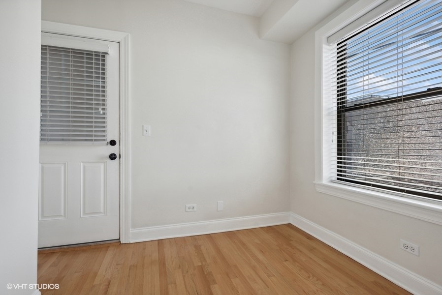 1137 West Grace Street, Unit 2E Chicago, IL 60613 - Photo 8 of 11 a view of an empty room with wooden floor and a window