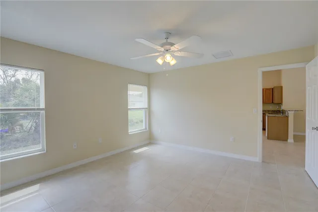 an empty room with windows and chandelier fan