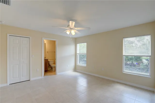an empty room with windows and fan