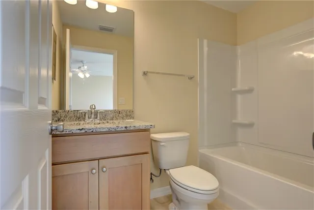 a bathroom with a granite countertop toilet a sink and a mirror
