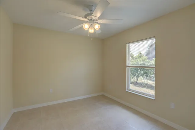 an empty room with windows and chandelier fan