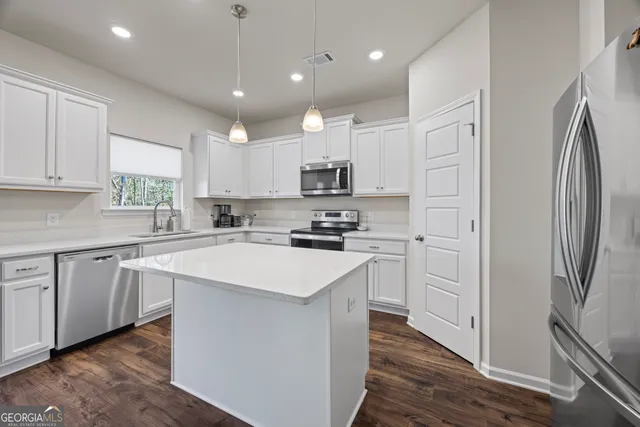 a kitchen with stainless steel appliances granite countertop a stove a sink and white cabinets