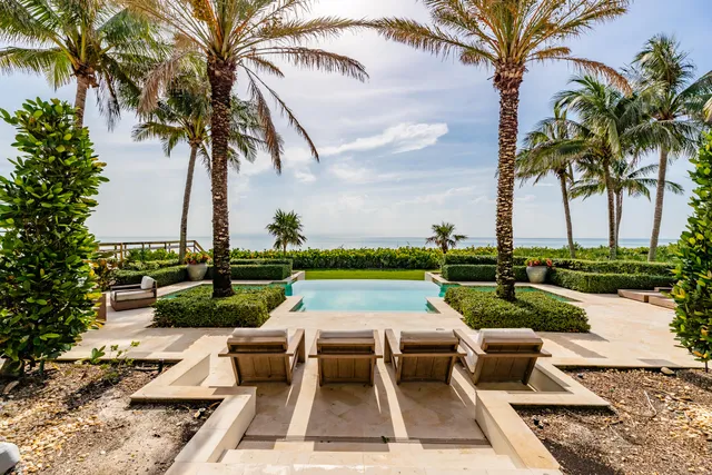 a view of a house with a yard and palm trees