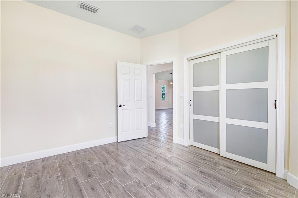 4909 Berryman Street Lehigh Acres, FL 33971 - Photo 11 of 30 Unfurnished bedroom featuring wood finish floors and a closet