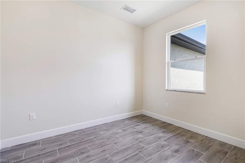 4909 Berryman Street Lehigh Acres, FL 33971 - Photo 12 of 30 Empty room with baseboards and wood finish floors