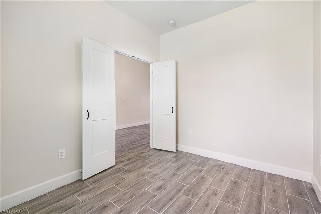 4909 Berryman Street Lehigh Acres, FL 33971 - Photo 13 of 30 Unfurnished room featuring baseboards and wood tiled floors
