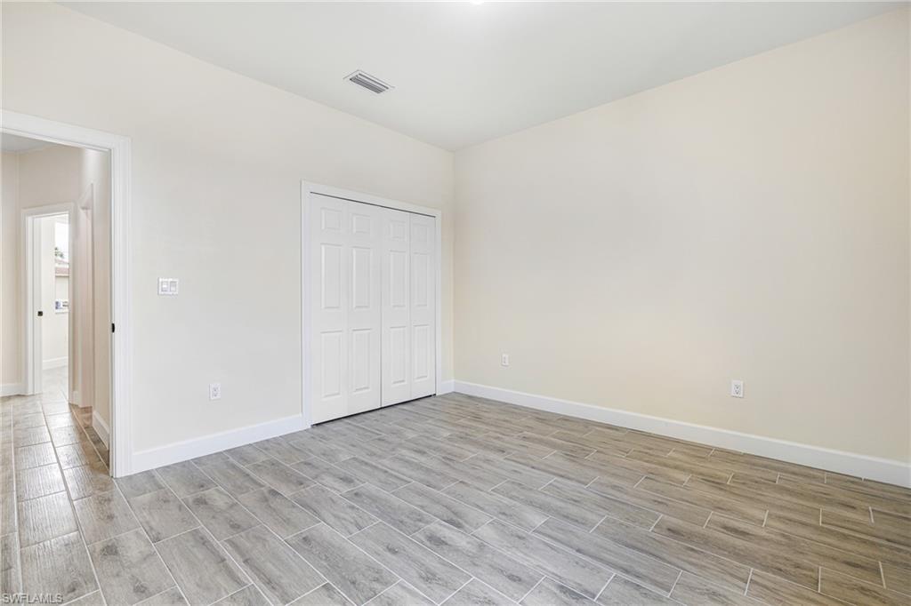 4909 Berryman Street Lehigh Acres, FL 33971 - Photo 16 of 30 Unfurnished bedroom featuring wood tiled floors and a closet