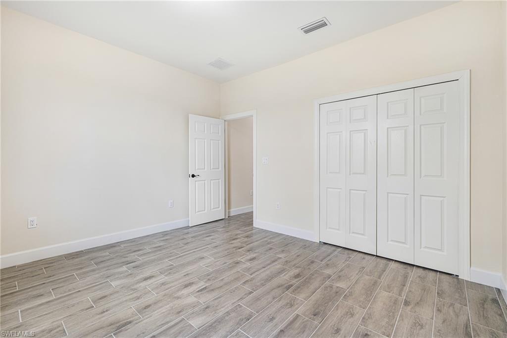 4909 Berryman Street Lehigh Acres, FL 33971 - Photo 17 of 30 Unfurnished bedroom featuring wood finish floors and a closet
