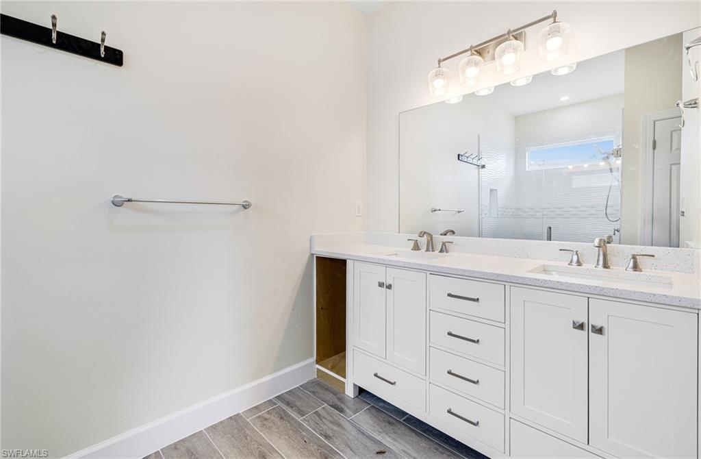 4909 Berryman Street Lehigh Acres, FL 33971 - Photo 21 of 30 Bathroom featuring double vanity, wood finish floors, and a shower stall