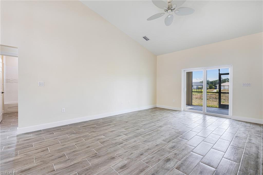 4909 Berryman Street Lehigh Acres, FL 33971 - Photo 7 of 30 Empty room featuring high vaulted ceiling, wood finish floors, and a ceiling fan