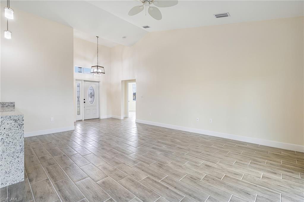 4909 Berryman Street Lehigh Acres, FL 33971 - Photo 8 of 30 Unfurnished living room featuring wood tiled floors, high vaulted ceiling, and a ceiling fan