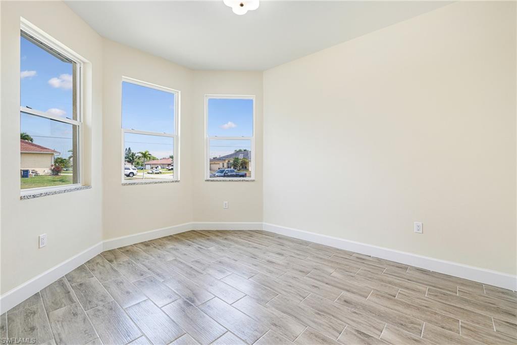 4909 Berryman Street Lehigh Acres, FL 33971 - Photo 9 of 30 Empty room with wood finish floors and baseboards