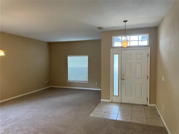 an empty room with windows and chandelier fan