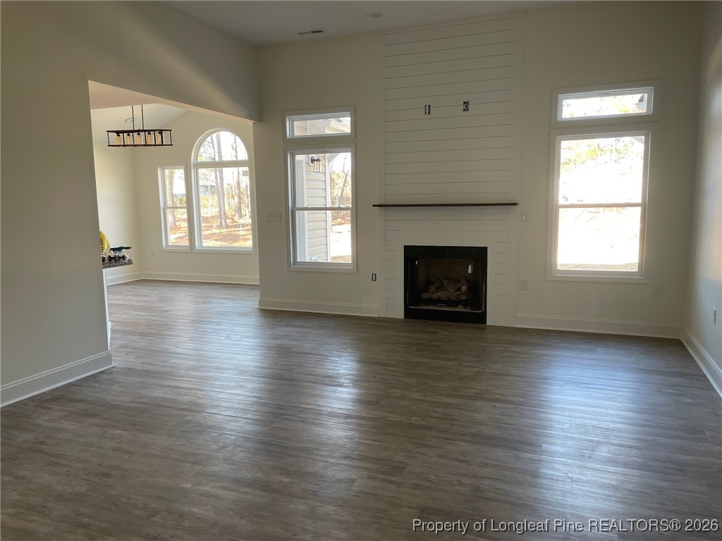 209 August Lane Raeford, NC 28376 - Photo 4 of 20 an empty room with wooden floor fireplace and windows