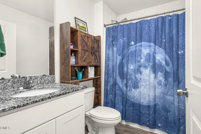 a bathroom with a granite countertop sink toilet and shower