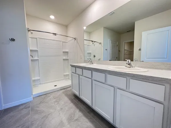 a spacious bathroom with a shower sink and mirror