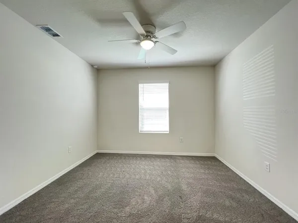 an empty room with a ceiling fan and window