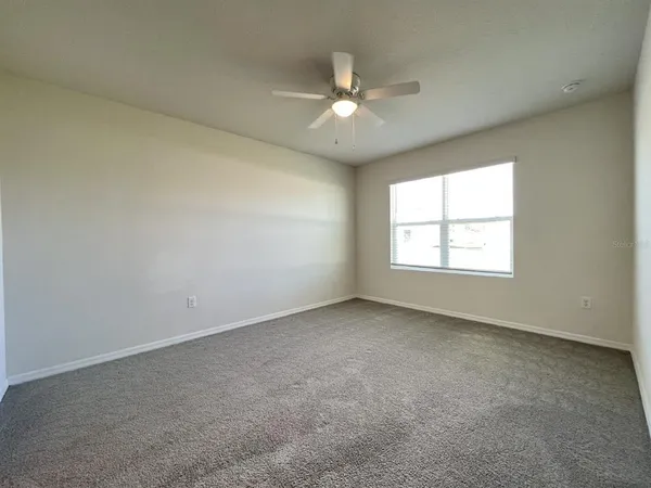 an empty room with a window and a fan