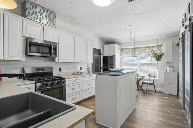 a kitchen with kitchen island white cabinets appliances and wooden floor