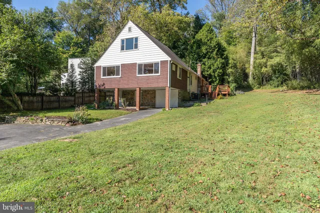 a view of a house with a yard and large trees