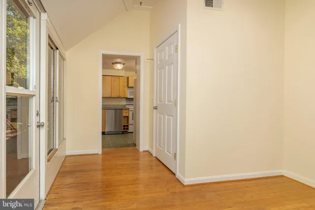 a view of a hallway with wooden floor and a bathroom
