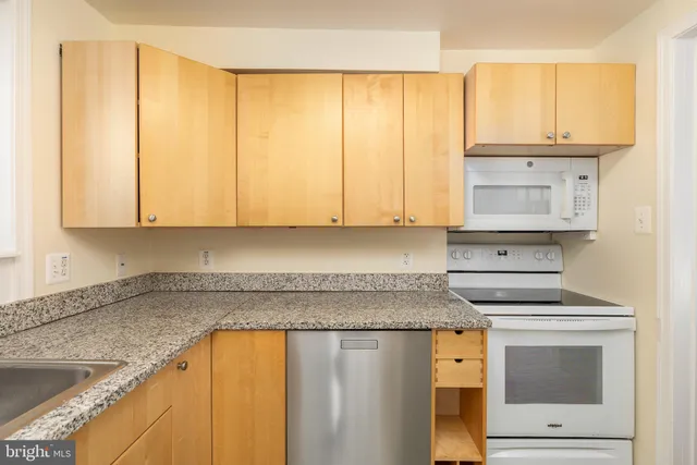 a kitchen with granite countertop white cabinets and white appliances