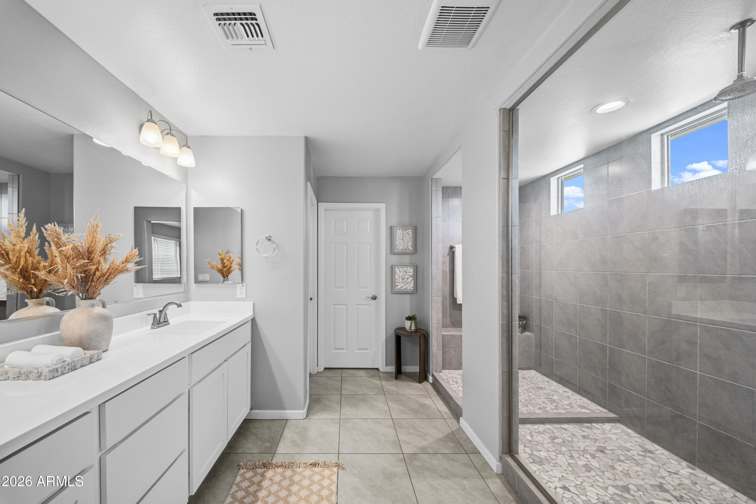 15754 West Madison Street Goodyear, AZ 85338 - Photo 17 of 35 a bathroom with a double vanity sink a large mirror a shower and a bathtub