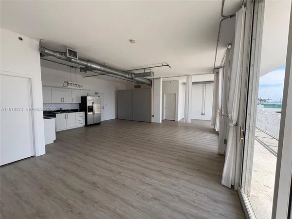 a view of empty room with wooden floor and electronic appliances