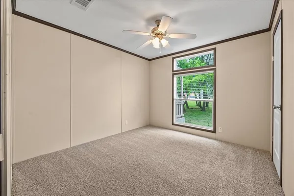 an empty room with windows and chandelier fan