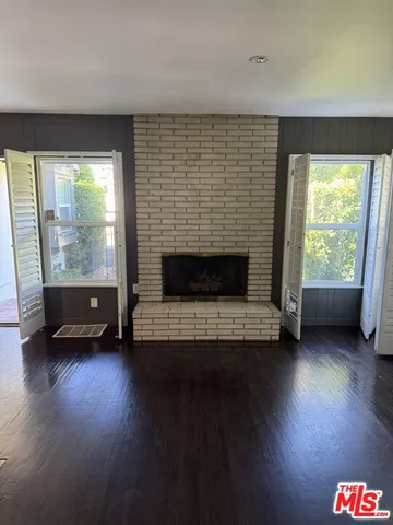 a view of a livingroom with fireplace wooden floor and windows