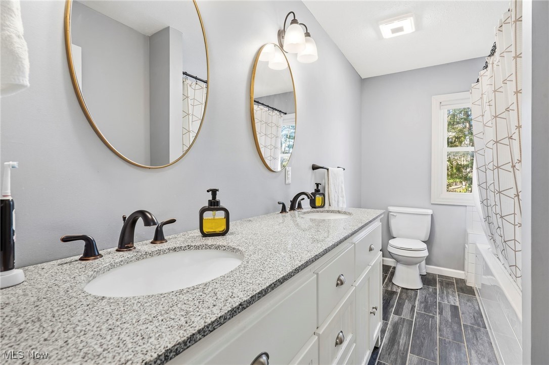 7153 Hudson Road Kent, OH 44240 - Photo 28 of 46 Full bathroom featuring double vanity, shower / tub combo with curtain, and wood tiled floors