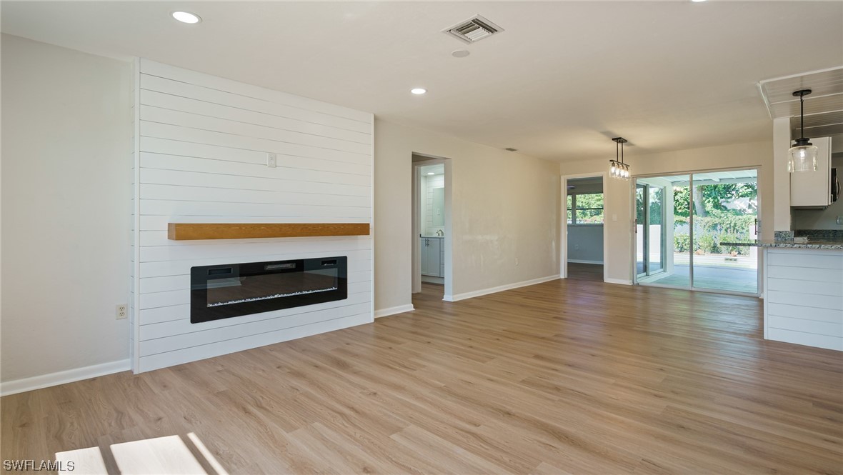 8631 Exeter Street Fort Myers, FL 33907 - Photo 3 of 23 an empty room with wooden floor fireplace and windows
