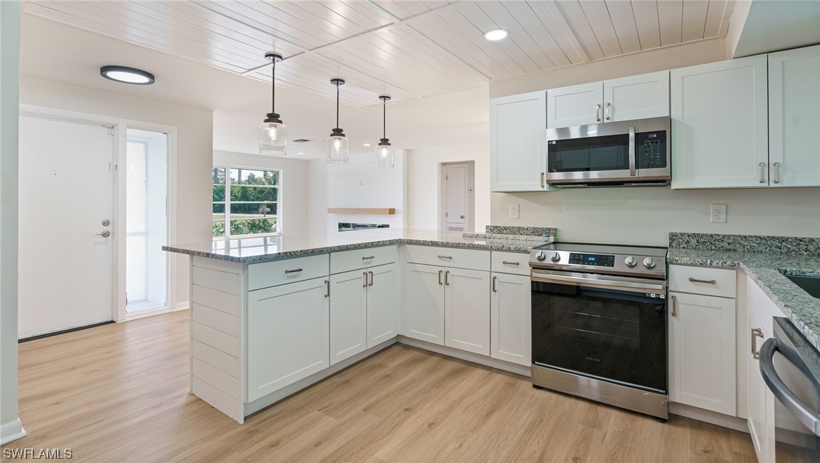 8631 Exeter Street Fort Myers, FL 33907 - Photo 7 of 23 a kitchen with stainless steel appliances granite countertop a stove a sink and a microwave