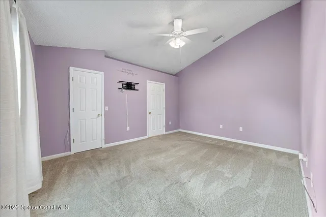 a view of an empty room with a chandelier fan