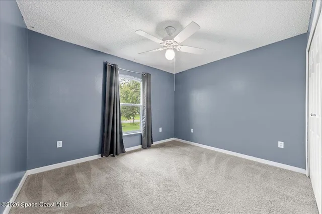 a view of an empty room with window and chandelier fan