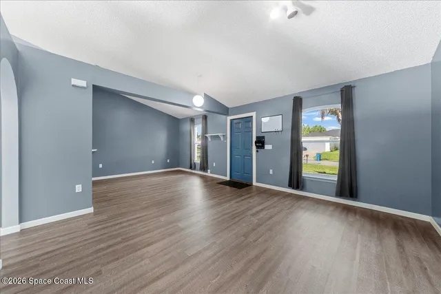 a view of an empty room with wooden floor and window