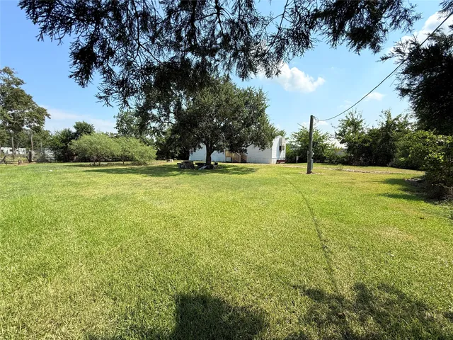 a view of a big yard with a fountain and large trees