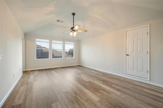 an empty room with wooden floor chandelier and windows