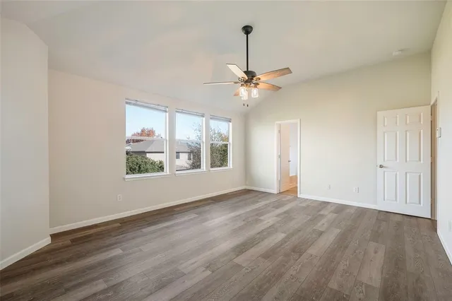 a view of an empty room with a window and wooden floor